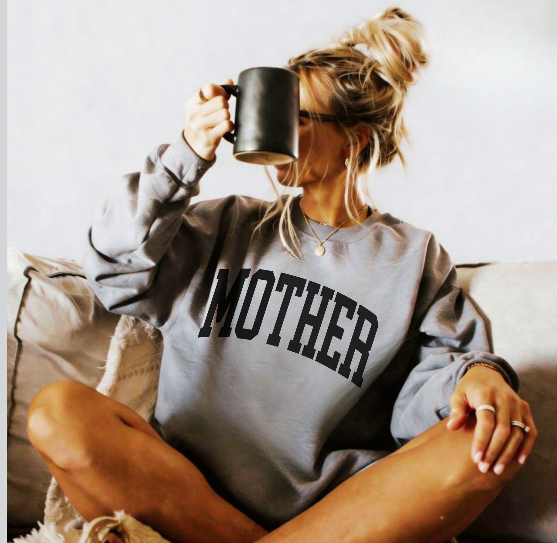 Woman wearing preppy grey Mother sweatshirt with collegiate in black text